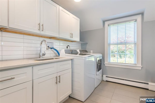 laundry area featuring washing machine and clothes dryer, cabinet space, a sink, light tile patterned floors, and a baseboard radiator