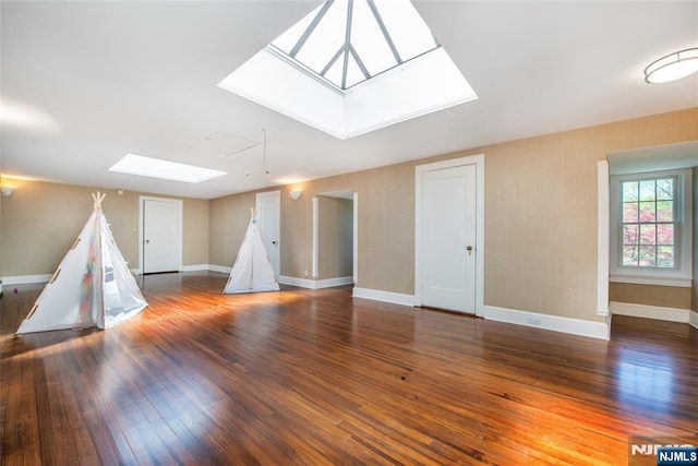 rec room with baseboards, wood finished floors, and a skylight