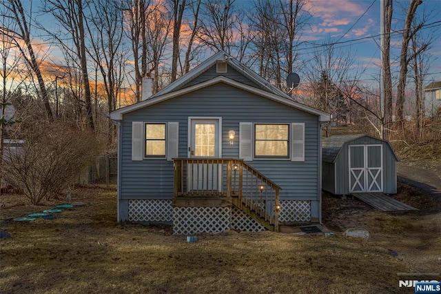 back of house featuring a storage shed, a lawn, and an outdoor structure