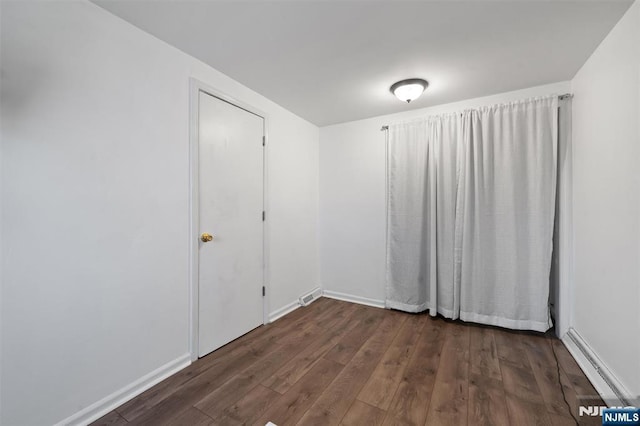 empty room featuring baseboards and dark wood-style flooring