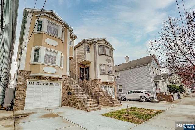 view of front of home with stucco siding, an attached garage, concrete driveway, and stairway