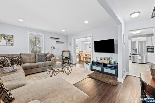 living room with baseboards, recessed lighting, light wood-style floors, and a notable chandelier