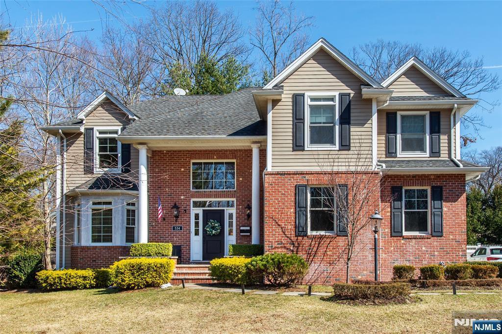 view of front of house with brick siding, a shingled roof, and a front yard