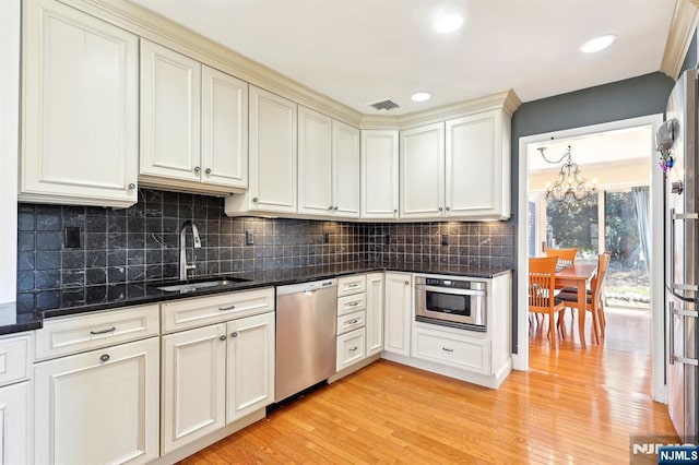 kitchen featuring visible vents, appliances with stainless steel finishes, a sink, light wood-style floors, and a notable chandelier