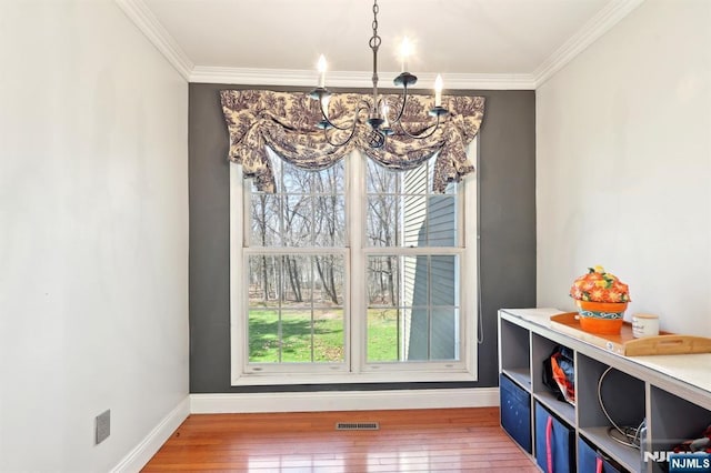 dining area featuring crown molding, wood-type flooring, baseboards, visible vents, and a notable chandelier