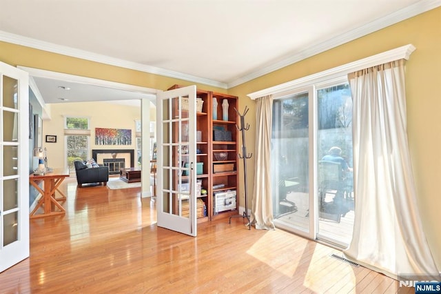interior space with hardwood / wood-style floors, ornamental molding, visible vents, and french doors