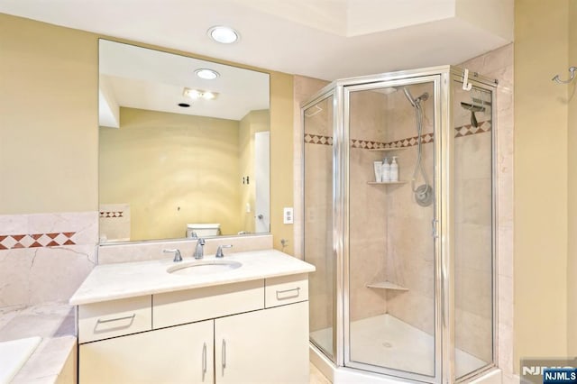 bathroom featuring vanity, toilet, a garden tub, and a shower stall