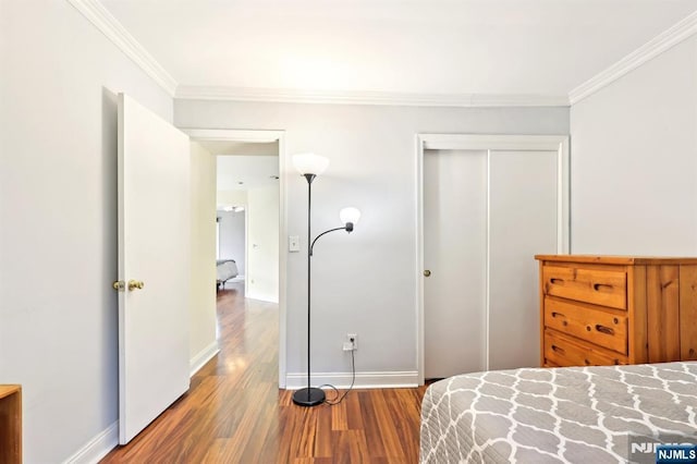 bedroom with baseboards, a closet, wood finished floors, and ornamental molding