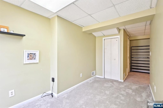 basement featuring baseboards, visible vents, a drop ceiling, and carpet
