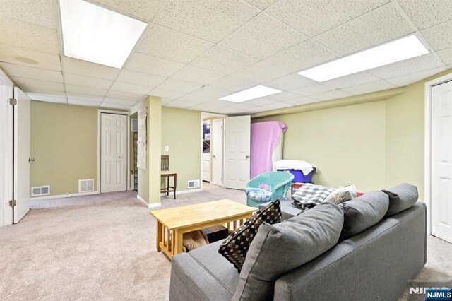 carpeted living room featuring a paneled ceiling, baseboards, and visible vents