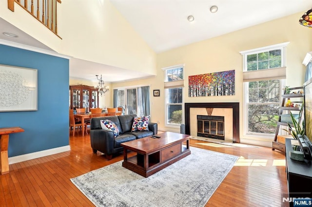 living room featuring hardwood / wood-style floors, high vaulted ceiling, a glass covered fireplace, and an inviting chandelier