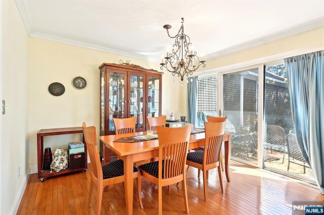 dining space featuring an inviting chandelier, ornamental molding, baseboards, and wood-type flooring