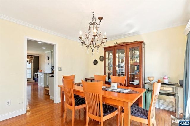 dining area featuring a notable chandelier, crown molding, and light wood-type flooring