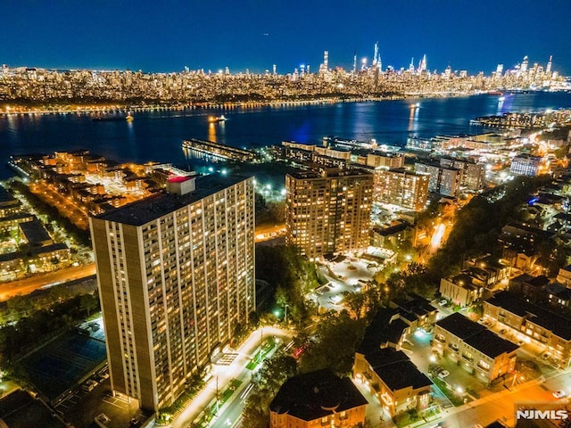 aerial view at night featuring a water view and a view of city lights