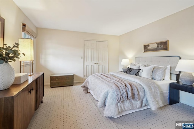 bedroom featuring a closet, baseboards, and light carpet