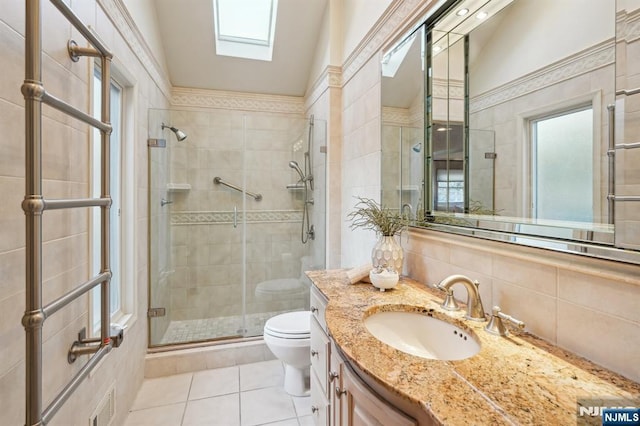 full bathroom featuring a skylight, a shower stall, toilet, tile patterned floors, and vanity