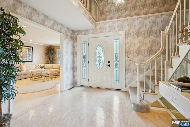 foyer entrance with stairway, ornamental molding, baseboards, a high ceiling, and visible vents