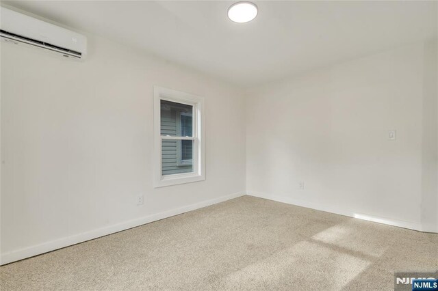 unfurnished room with baseboards and an AC wall unit