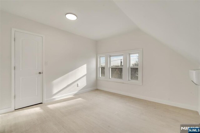 additional living space featuring light wood-style floors, baseboards, and vaulted ceiling