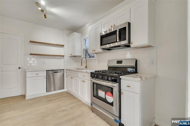 kitchen with light stone countertops, a sink, open shelves, and appliances with stainless steel finishes