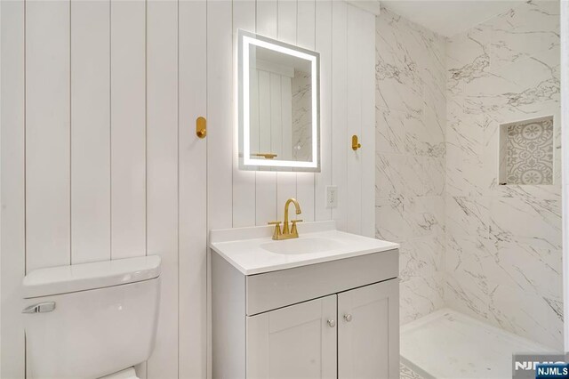 full bathroom with toilet, vanity, and walk in shower