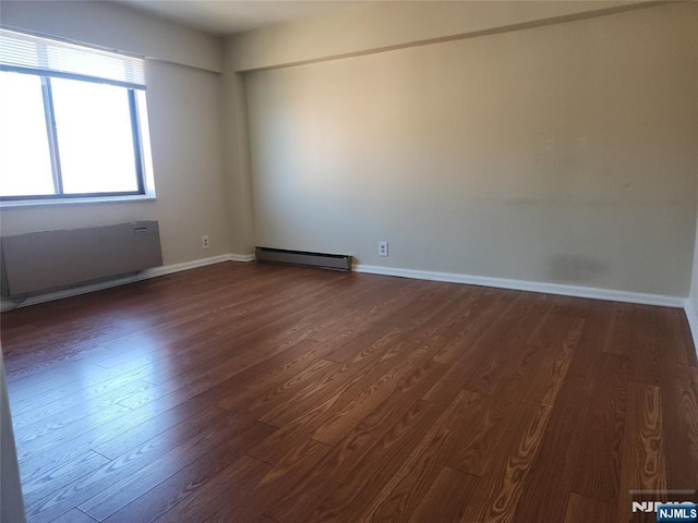 empty room with dark wood finished floors, baseboards, and baseboard heating