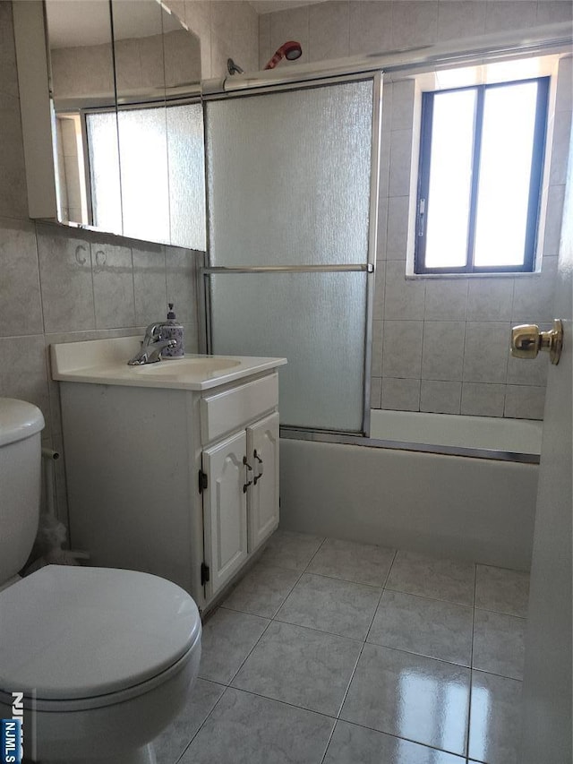 full bath featuring tile walls, toilet, tile patterned floors, vanity, and enclosed tub / shower combo