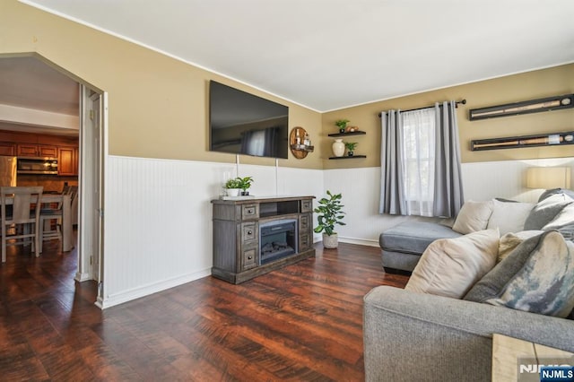 living area featuring a wainscoted wall, a fireplace, and wood finished floors