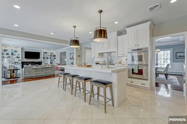 kitchen featuring light countertops, double oven, a kitchen breakfast bar, light tile patterned floors, and visible vents
