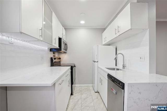 kitchen with appliances with stainless steel finishes, a sink, decorative backsplash, light marble finish floors, and light stone countertops
