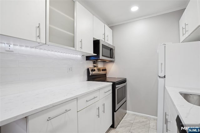 kitchen featuring appliances with stainless steel finishes, light marble finish floors, decorative backsplash, glass insert cabinets, and white cabinets