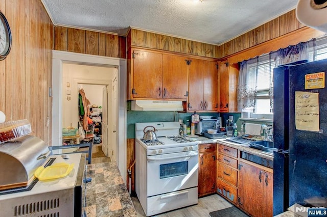 162 Summer St, Orange, NJ 07050 - kitchen featuring white range with gas cooktop, wooden walls, a textured ceiling, freestanding refrigerator, and under cabinet range hood