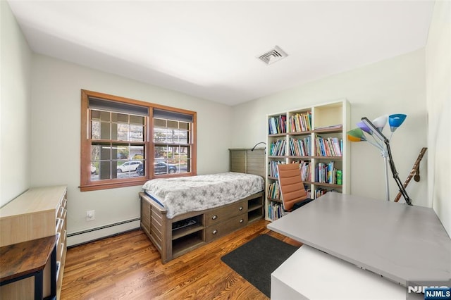 bedroom with visible vents, wood finished floors, and baseboard heating