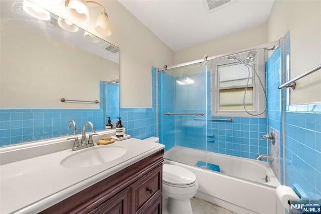 bathroom with visible vents, tile walls, bathtub / shower combination, vanity, and toilet