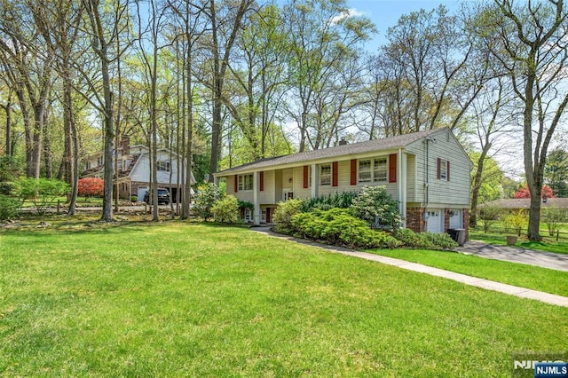 raised ranch with a garage, driveway, and a front yard