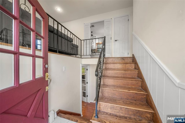 staircase with wainscoting, a decorative wall, and baseboard heating