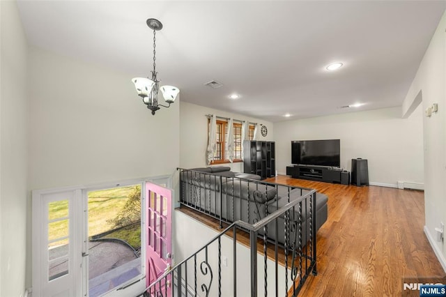 living room featuring a notable chandelier, baseboard heating, recessed lighting, wood finished floors, and visible vents