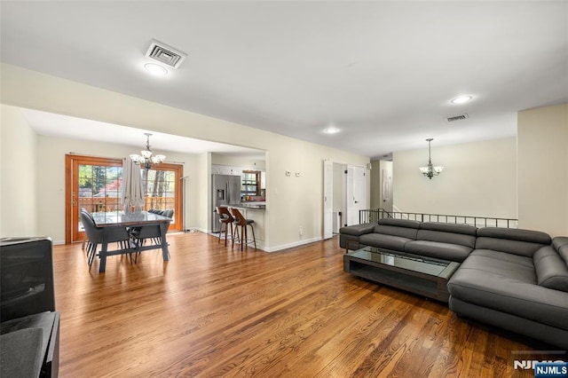 living room with visible vents, wood finished floors, and a notable chandelier