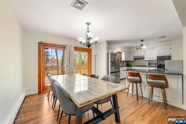 dining area with a baseboard heating unit, a chandelier, light wood-style flooring, and visible vents