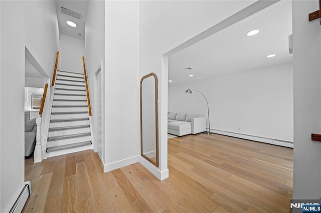 staircase with visible vents, baseboard heating, wood finished floors, baseboards, and a baseboard heating unit