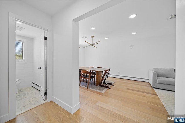 hallway with recessed lighting, an inviting chandelier, light wood-style flooring, and a baseboard radiator