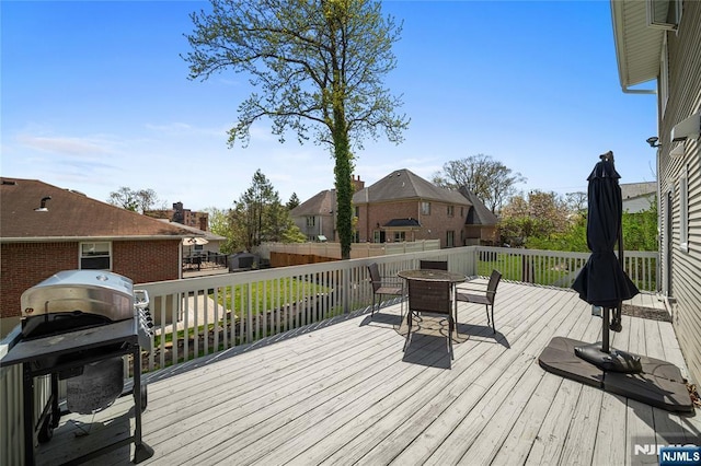wooden terrace with fence, a residential view, outdoor dining area, and a grill
