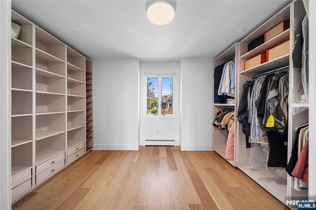 spacious closet featuring light wood finished floors and a baseboard heating unit