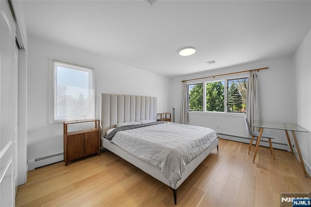bedroom featuring visible vents, a baseboard radiator, and light wood finished floors