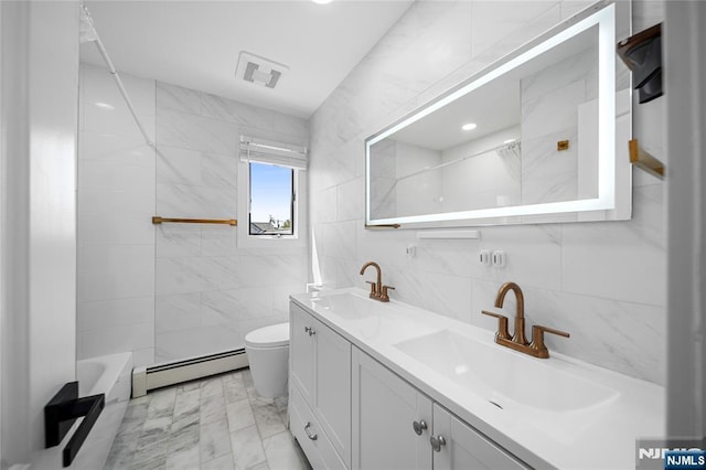 bathroom with a sink, baseboard heating, toilet, and tile walls