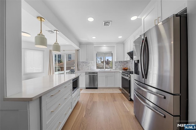 kitchen with visible vents, appliances with stainless steel finishes, white cabinets, and tasteful backsplash