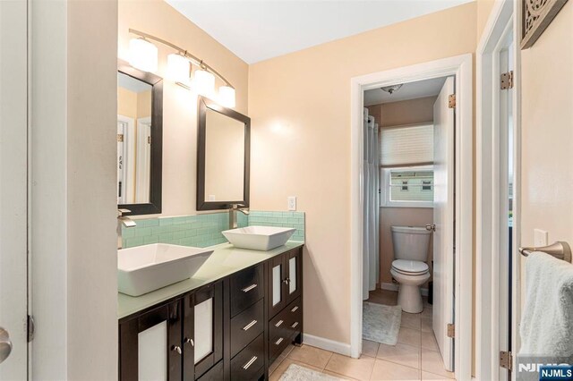 bathroom featuring tile patterned floors, a sink, double vanity, and toilet