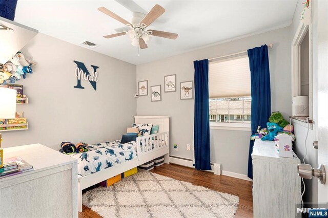 bedroom featuring wood finished floors, visible vents, baseboards, a baseboard radiator, and ceiling fan