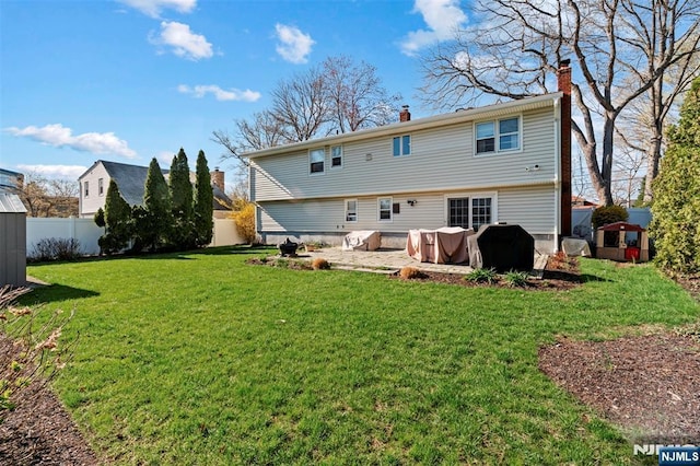 back of house featuring a lawn, a fenced backyard, and a chimney