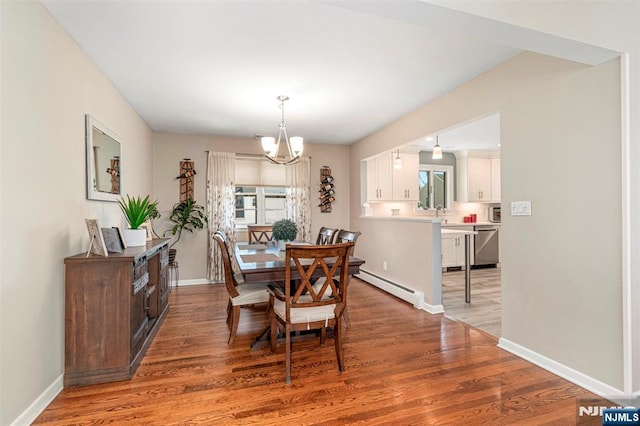 dining room featuring a chandelier, light wood-type flooring, baseboards, and baseboard heating